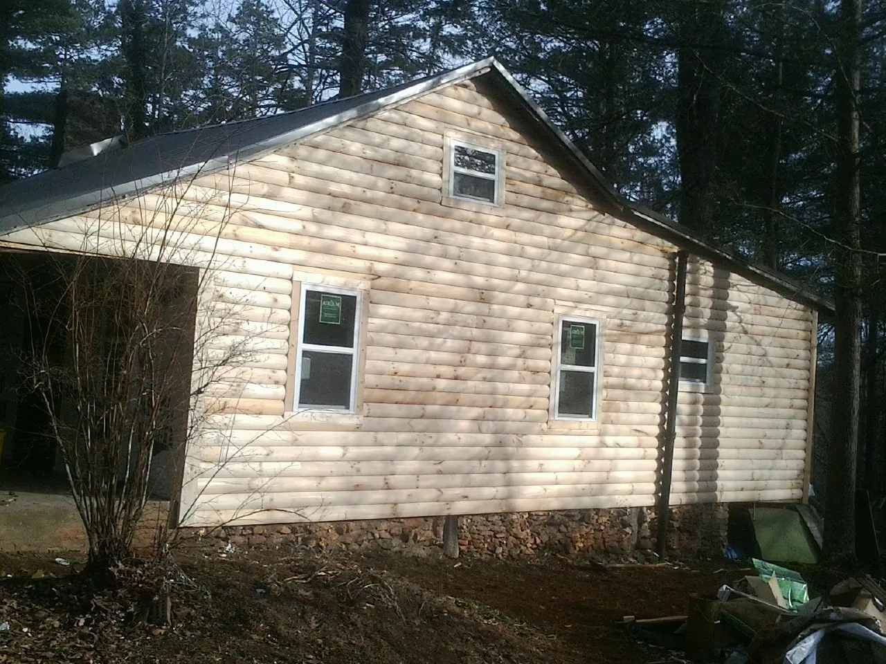 New log siding and dark metal roofing on a gable end in Great Meadows
