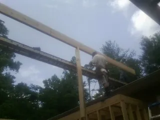Carpenter setting a ridge beam over a new addition frame — Ice Dam Removal by Roofing Brothers in Great Meadows