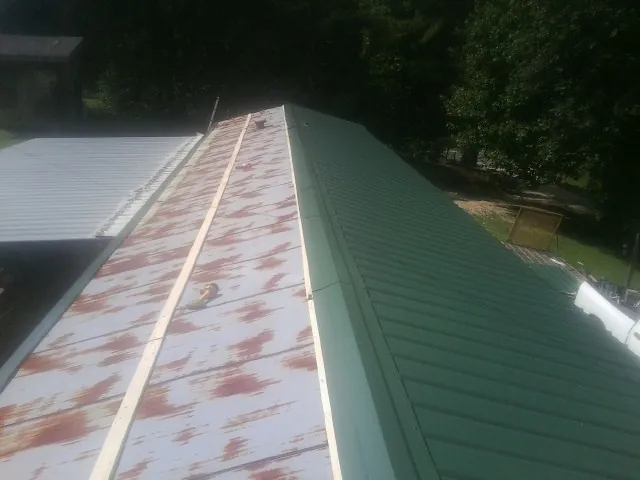 Old rusted panels beside newly installed green metal roofing — Wind Damage Roof Repair by Roofing Brothers in Great Meadows