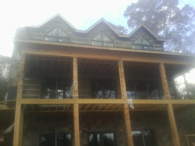 Dormers and porch framing on a large log home under construction — Roof Coating work by our crew in Great Meadows