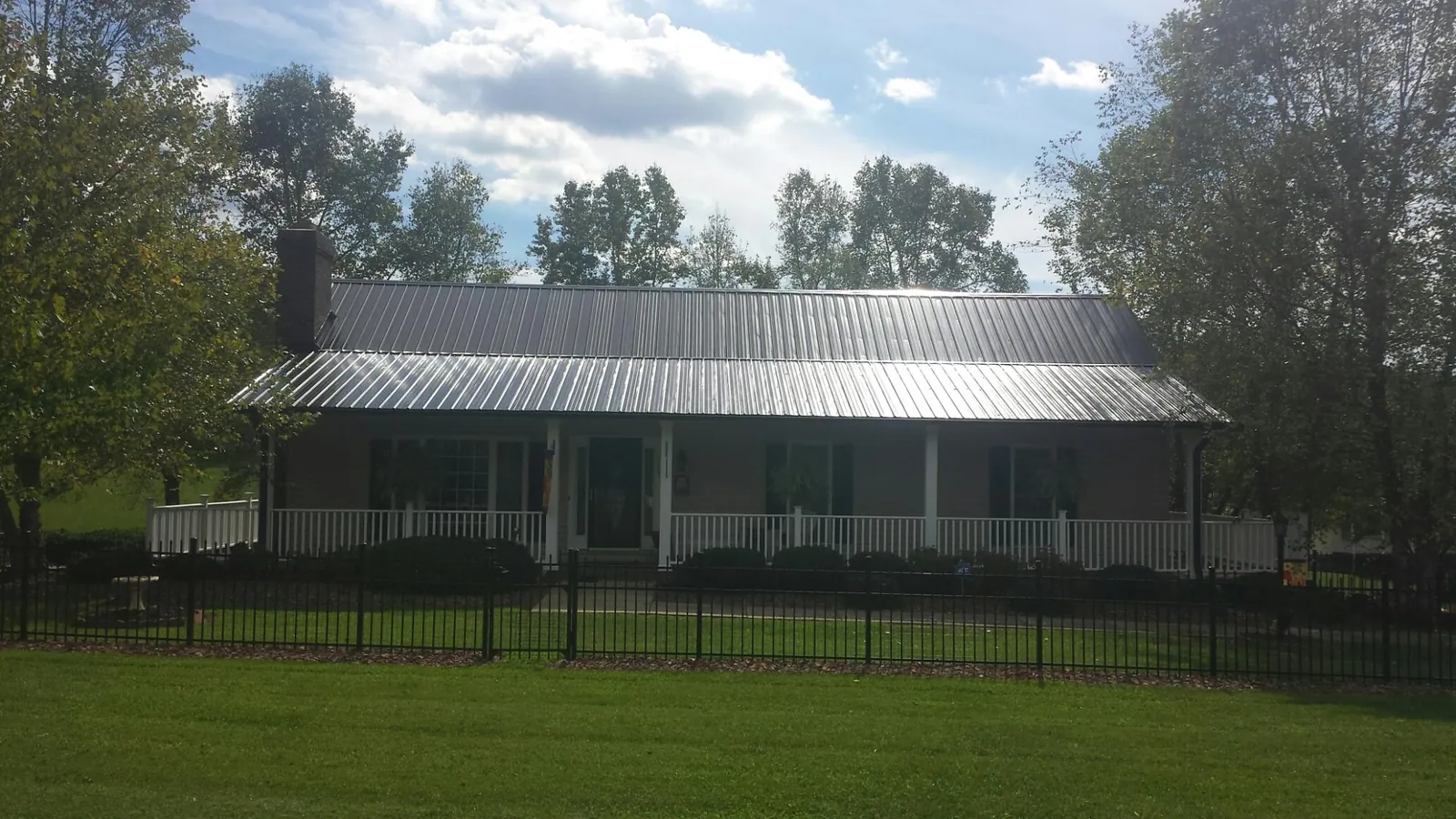 Gray metal roof on a brick ranch with a full width front porch — Gutter Guard Installation work by our crew in Great Meadows