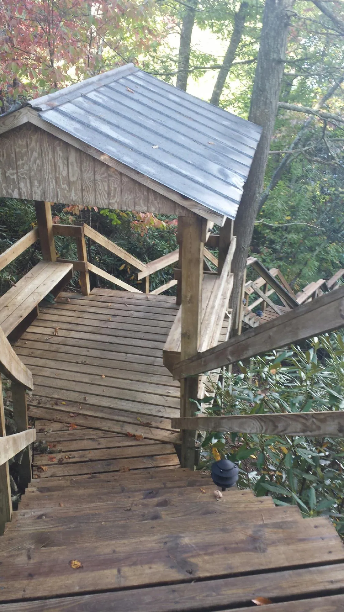 Metal roofed shelter over wooden steps on a wooded walkway — Skylight Repair & Installation work by our crew in Great Meadows