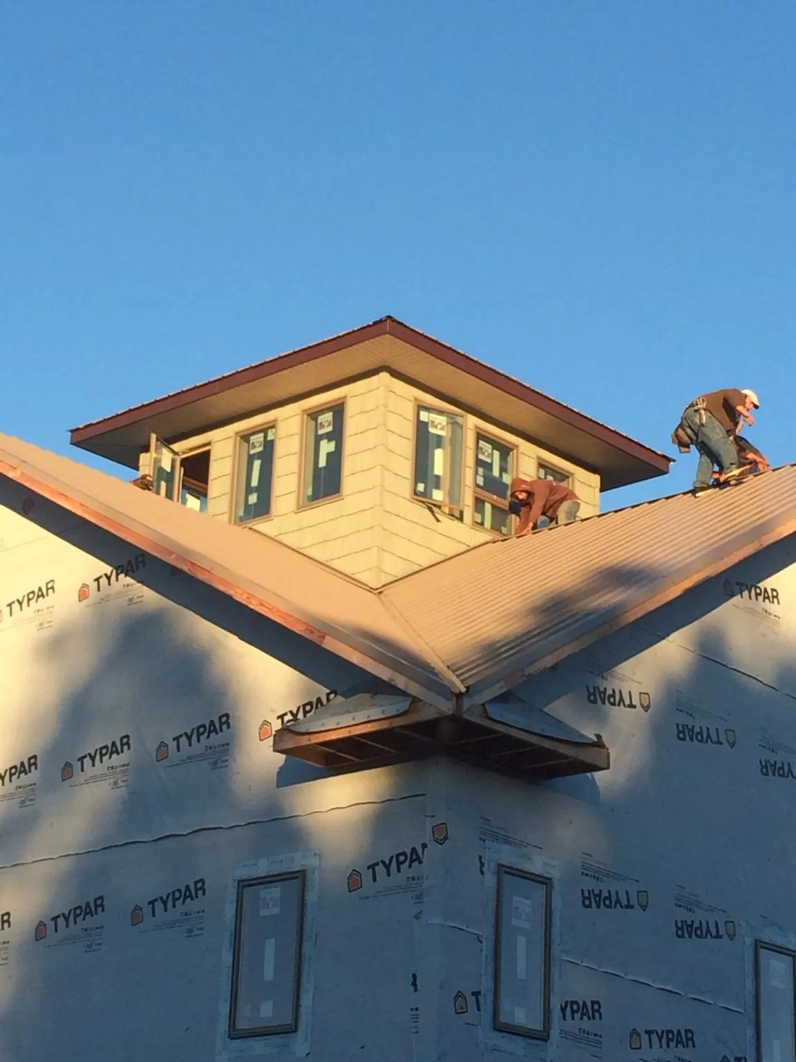 Roofers working around a rooftop cupola on a new metal roof at sunset — Roof Waterproofing in Great Meadows by Roofing Brothers